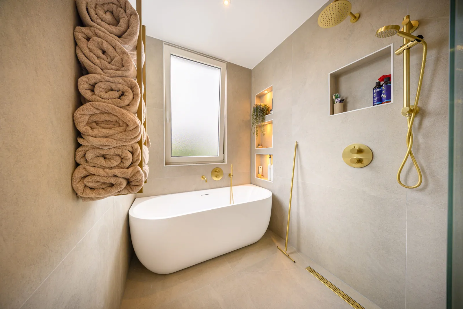 Badkamer met ligbad, handdoeken en goudkleurige kranen, Schiedam