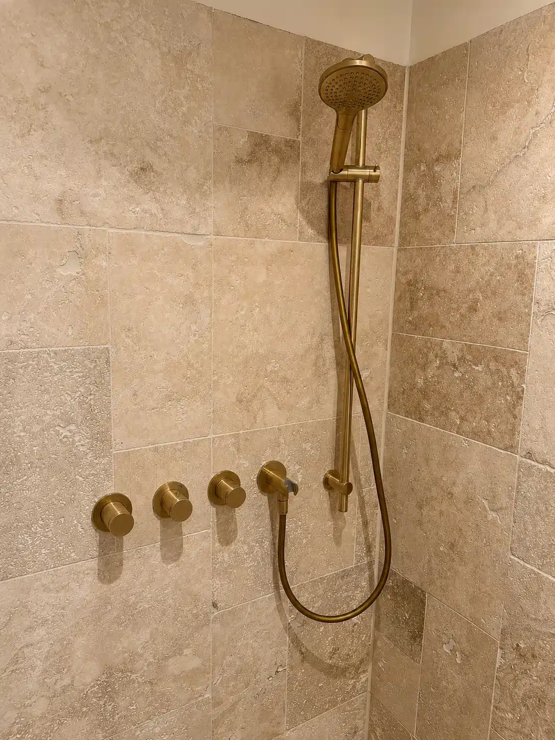 Douche met goudkleurige kranen en natuursteen tegels, Den Haag