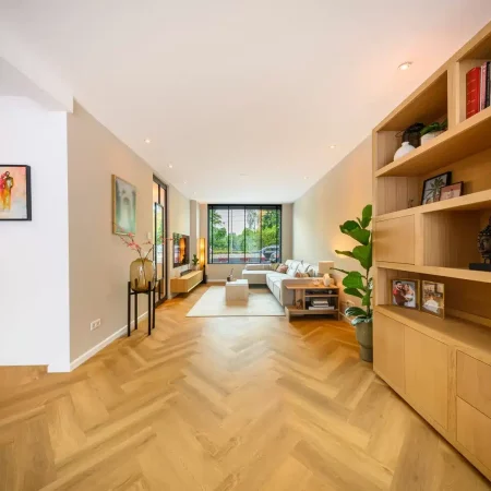 Woonkamer met houten kastenwand en visgraatvloer na renovatie, Schiedam